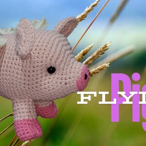 May include: A pink crocheted pig with white wings is flying in the air. The pig has a pink nose and black eyes. The background is a field of tall grass.
