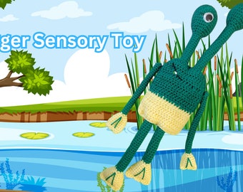 May include: A green and yellow crocheted frog toy with long arms and legs. The frog is sitting in a pond with lily pads and reeds.