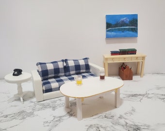 May include: A white living room set with a blue and white checkered couch, a white coffee table, a white side table with a black rotary phone, and a wooden console table with books and a wooden box.