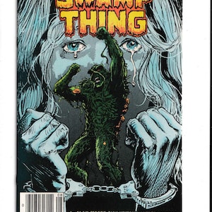 May include: Comic book cover featuring "Swamp Thing." The artwork depicts a green, plant-like creature breaking free, set against a backdrop of a crying woman and handcuffs. The title is in bold, yellow letters.