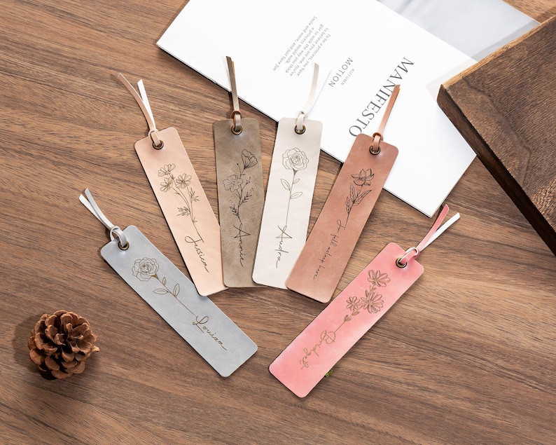 May include: Five leather bookmarks with floral designs and personalized names. The names are "Justice", "Amelia", "Audrey", "To tell you the truth", and "Blooming".