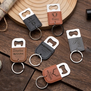 May include: Six different leather bottle opener keychains with engraved names and designs. The keychains are brown, black, and grey.