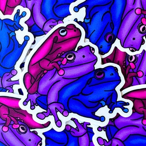 May include: A selection of frog stickers in various shades of blue, purple, and pink. The cartoon frogs have white outlines. The stickers are arranged in a random pattern, with some overlapping each other. The overall theme is playful.