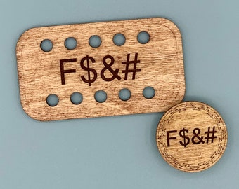 Peut inclure: Deux dessous de verre en bois avec le texte "F$&#". L'un est rectangulaire avec dix trous, l'autre est rond avec une bordure décorative. Les deux sont brun clair avec du texte brun foncé.