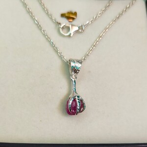 May include: A silver necklace with a claw pendant holding a pink gemstone.
