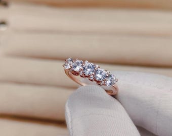 Puede incluir: Un anillo de banda de oro rosa con seis piedras redondas de circonita cúbica transparentes.