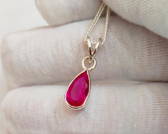 May include: A teardrop-shaped pendant necklace with a bright pink gemstone set in sterling silver.