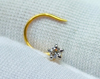 May include: A gold nose ring with a single, clear diamond set in a star-shaped prong setting.