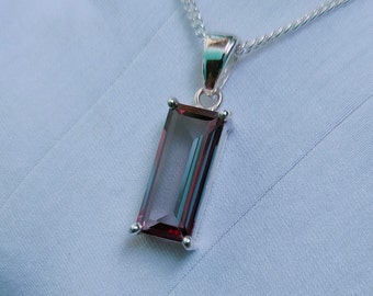 May include: A silver chain necklace with a pendant featuring a rectangular, faceted, dark purple gemstone.