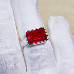 May include: A silver ring with a large, rectangular, red gemstone.