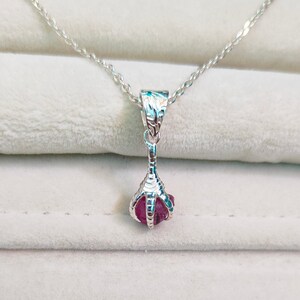 May include: A silver necklace with a pink gemstone pendant shaped like a claw.