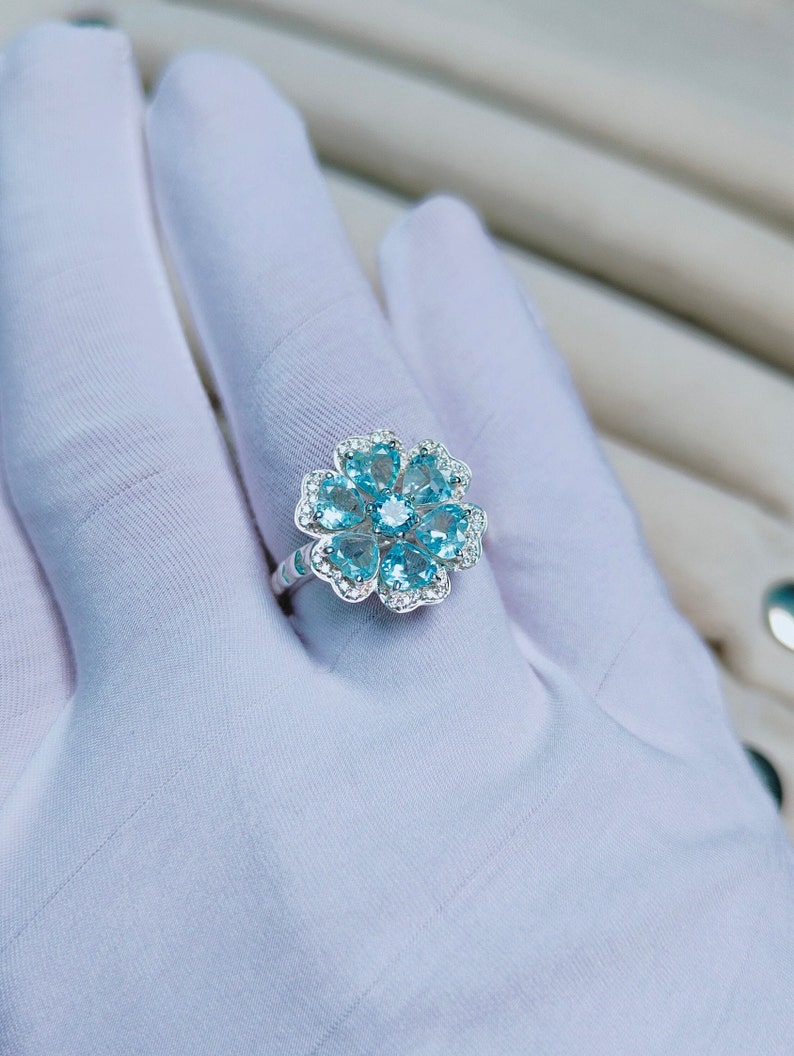 May include: A silver ring with a flower design featuring blue gemstones and white accents.