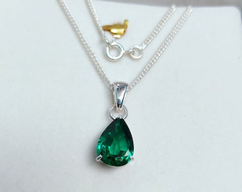 May include: A silver chain necklace with a pear-shaped green gemstone pendant.