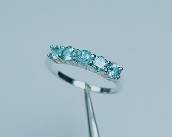 May include: A silver ring with six light blue gemstones set in a row.