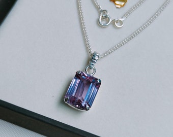 May include: A silver chain necklace with a pendant featuring a large, rectangular, faceted amethyst gemstone.
