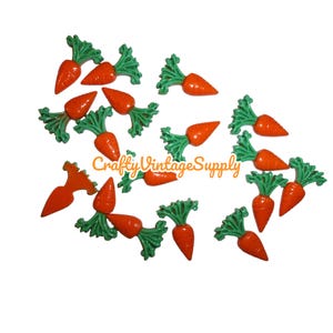 May include: A collection of orange carrot-shaped embellishments with green leafy tops. The image includes the text "Crafty Vintage Supply". These decorative carrots are likely used for crafts or seasonal decor.