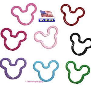 May include: Assortment of ten Mickey Mouse shaped metal keychains in various colors, including pink, red, black, purple, blue, and green.  The keychains are all the same size and shape, and they are all made of metal.  The keychains are arranged in a circle on a white background.  US Seller.