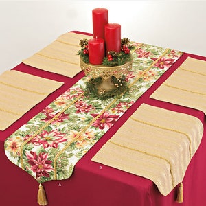 Op de afbeelding: Een rode tafelkleed met vier placemats en een tafelrunner. De placemats zijn beige met gouden rand. De tafelrunner is wit met een rood en groen bloemenpatroon en gouden rand. Er staan drie rode kaarsen op een gouden metalen standaard in het midden van de tafelrunner. De kaarsen zijn omringd door een groene krans met rode bessen.