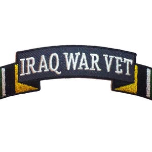 May include: A navy blue embroidered patch with the text "IRAQ WAR VET" in white. The patch has a banner shape with red, yellow, black, and green accents on the ends.