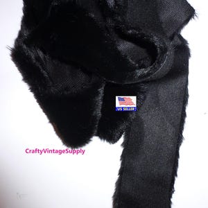 May include: Black faux fur trim with a smooth, black fabric backing. The trim is approximately 1 inch wide and is perfect for adding a touch of luxury to any project.
