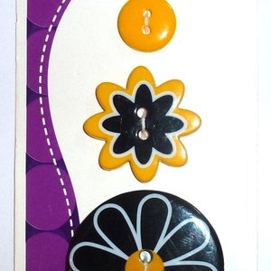 Könnte beinhalten: Drei Knöpfe mit einem Gänseblümchen-Design. Die Knöpfe sind schwarz mit weißen Umrandungen und gelben Zentren. Das Wort "Buttons" ist auf der Karte gedruckt.