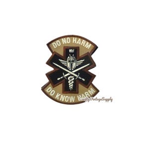 May include: A patch with the text "DO NO HARM" and "DO KNOW HARM" in a curved design. The center features a medical symbol with a helmet, crossed swords, and a staff with a snake. The patch is brown, black, and white.