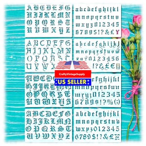 May include: A set of six white stencils with teal lettering in an old English font. Each stencil features uppercase and lowercase letters, numbers, and symbols. The stencils are arranged on a teal wooden surface.