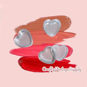Peut inclure: Des embellissements en verre transparent en forme de cœur sur un fond de coups de rouge à lèvres dans les tons de rouge, corail et marron. Le texte "Crafty Vintage Supply" est visible en bas à droite.