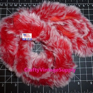 May include: Red and white faux fur trim, approximately 1.5 inches wide. The fur is soft and fluffy, with a white base and red tips. The trim is shown on a black grid background. US SELLER: