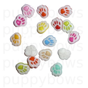 Op de afbeelding: Assortiment van kleurrijke poot afdruk knoppen met witte centra. De knoppen zijn gemaakt van plastic en hebben een glanzende afwerking.
