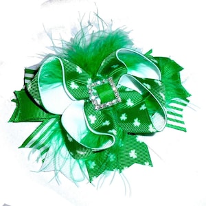 May include: A green and white shamrock patterned hair bow with a green feather accent and a sparkly green rhinestone center.