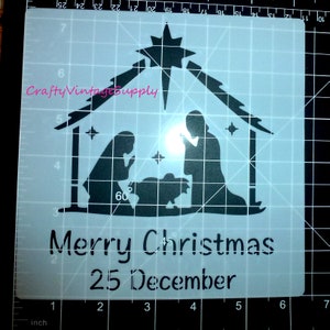 May include: A white stencil featuring a black silhouette of the nativity scene. The stencil includes a star, a manger, a baby, Mary, Joseph, and the text "Merry Christmas 25 December".