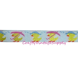 May include: A blue and white ribbon with a repeating pattern of yellow ducks wearing pink and blue umbrellas. The ducks are facing left and the umbrellas are open.