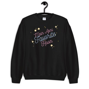 May include: Black sweatshirt with the text "Main Apni Favorite Hoon" in pink and blue lettering with gold glitter accents.