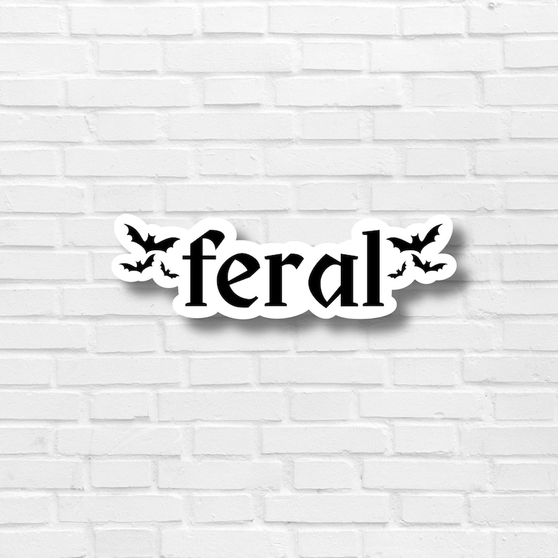 May include: A white brick wall with a black and white sticker that says "feral" with bats around the word.