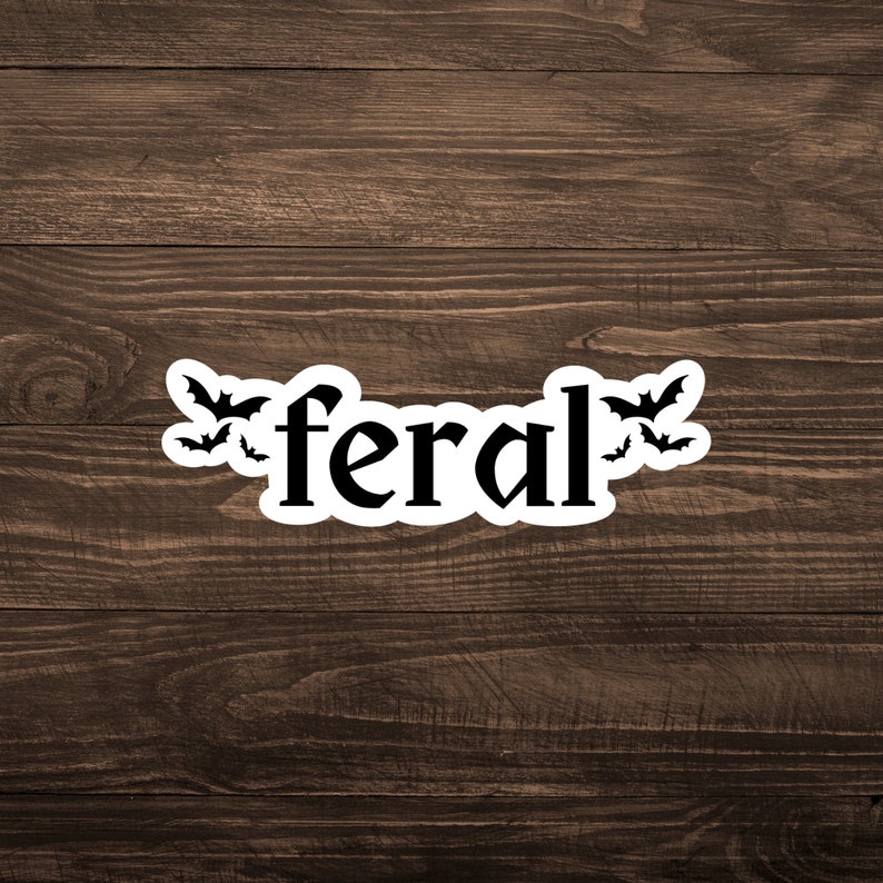 May include: A white sticker with the word "feral" in black text. There are three black bats flying around the word.
