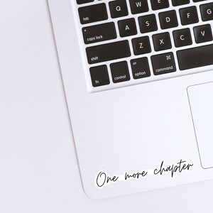 Op de afbeelding: Een witte laptop met een zwart toetsenbord en een sticker met de tekst "One more chapter" in de rechterbenedenhoek.