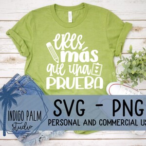 Peut inclure: Un t-shirt vert clair avec l'expression espagnole "Eres más que una prueba" en blanc. Le design comprend un crayon et un presse-papiers. Le t-shirt est associé à un short en jean et une basket blanche.