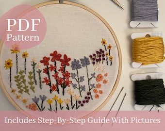 Può includere: Un telaio da ricamo con un disegno floreale in filo rosso, giallo, viola e arancione. Il testo "PDF Pattern" e "Includes Step-By-Step Guide With Pictures" sono visibili. Sono presenti anche rocchetti di filo grigio, giallo e verde.