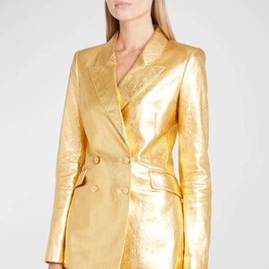 Könnte beinhalten: Ein goldfarbener Blazer aus Metall mit doppelreihigem Verschluss und Reverskragen.