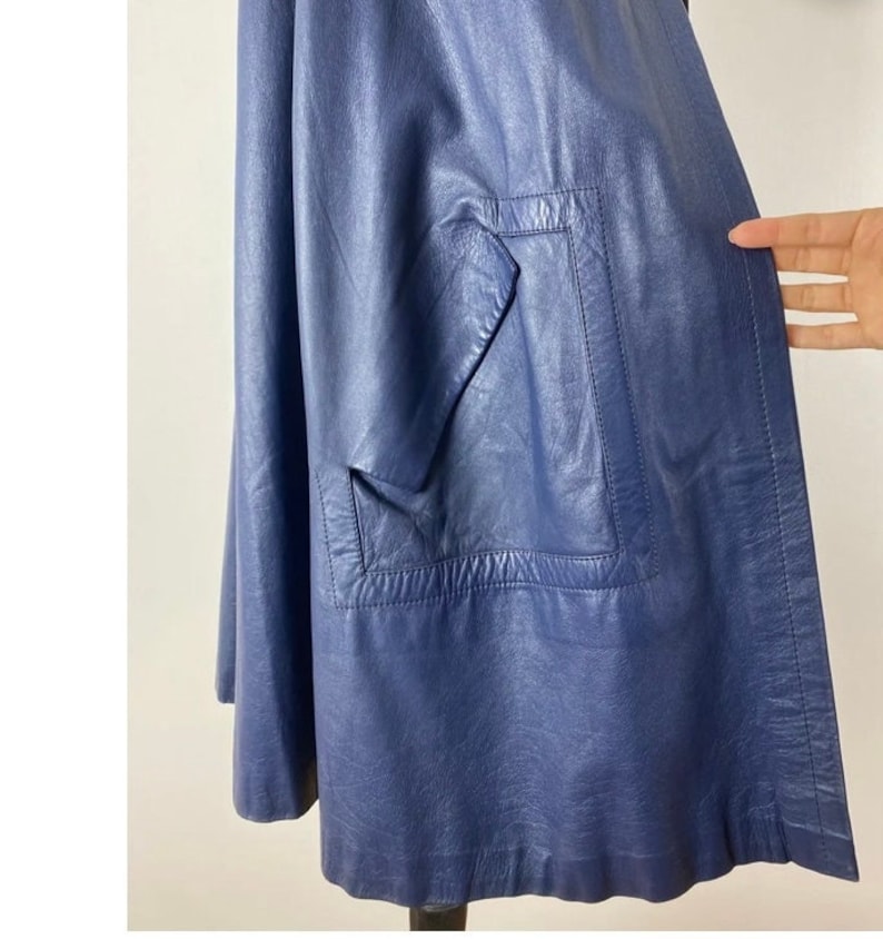 May include: A dark blue leather jacket with a single pocket on the front.