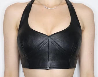 May include: A black leather halter top with a sweetheart neckline and a cropped fit.