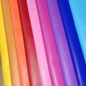 May include: A collection of colorful leather sheets in various shades, including green, yellow, orange, red, pink, purple, and blue. The sheets are arranged side by side, showcasing a spectrum of colors and textures, suitable for crafting.