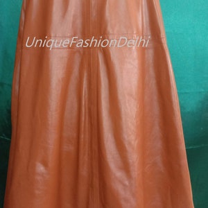 May include: A brown leather cape with a collar and a seam down the back. The cape is on a mannequin against a green background. The text "UniqueFashionDelhi" is printed on the cape.
