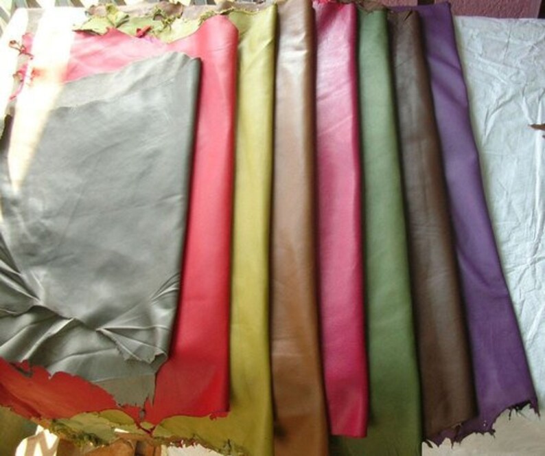 Pode incluir: Uma cole&ccedil;&atilde;o de nove amostras de couro em v&aacute;rias cores, incluindo cinza, vermelho, amarelo, marrom, rosa, verde, marrom escuro e roxo. As amostras est&atilde;o dispostas em uma fila, com a amostra cinza na parte superior e a amostra roxa na parte inferior.