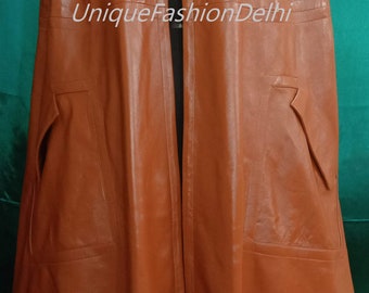 May include: A brown leather cape with a collar and a long, flowing design. The cape has a slit down the back and two pockets on the sides. The text "UniqueFashionDelhi" is printed on the front of the cape.