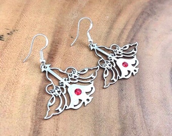 May include: A pair of silver earrings with a red rhinestone in the center of each earring. The earrings are shaped like a stylized spade playing card.