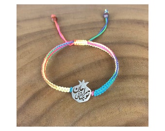 May include: A colorful braided bracelet with a silver pomegranate charm featuring the Persian phrase "Good Luck".