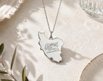 May include: A silver-colored pendant necklace featuring a detailed outline of Iran. The pendant showcases a lion and sun emblem. The necklace hangs on a delicate chain, perfect for everyday wear.