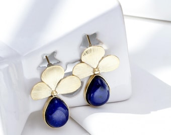 May include: Gold flower-shaped earrings with a teardrop-shaped blue gemstone hanging from each flower.
